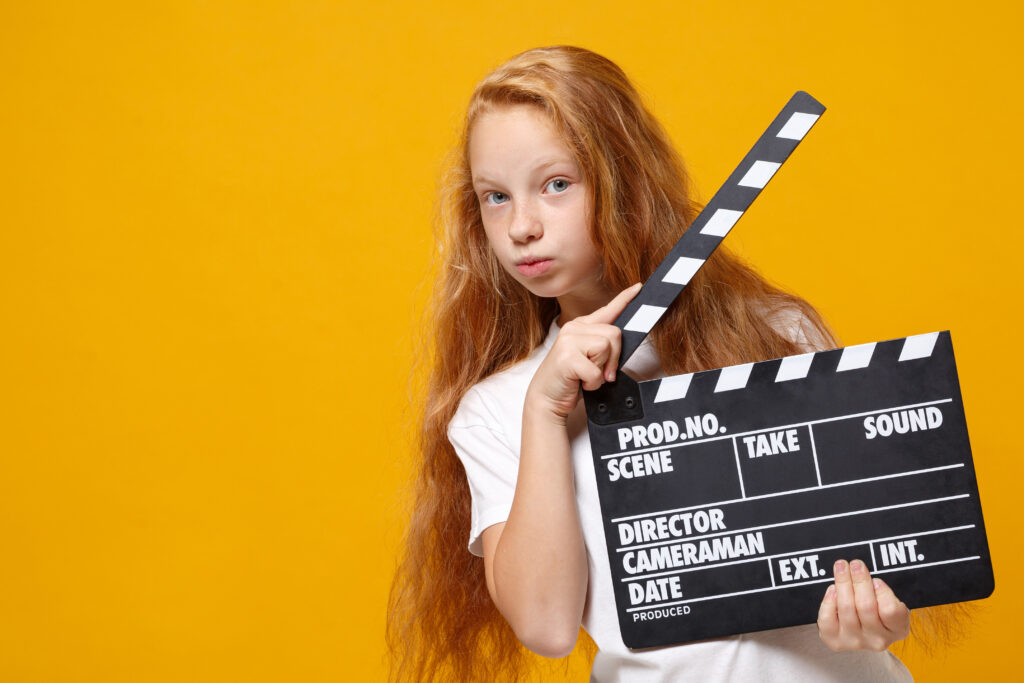Girl holding clapperboard for film shoot.